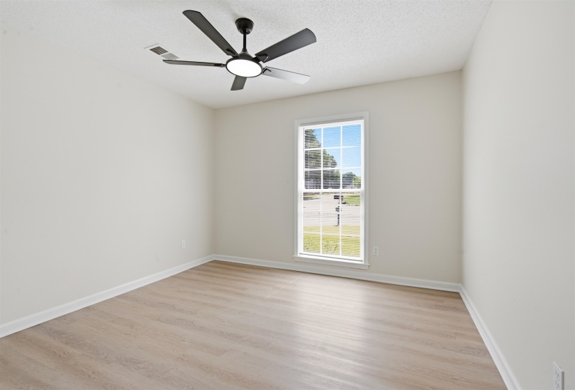 Room featuring a modern black ceiling fan, light wood-finish flooring, white baseboards, and a framed window
