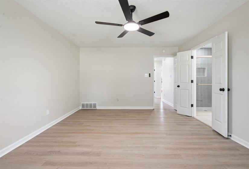 Spacious room featuring wood-finish flooring, light gray walls, and white baseboards