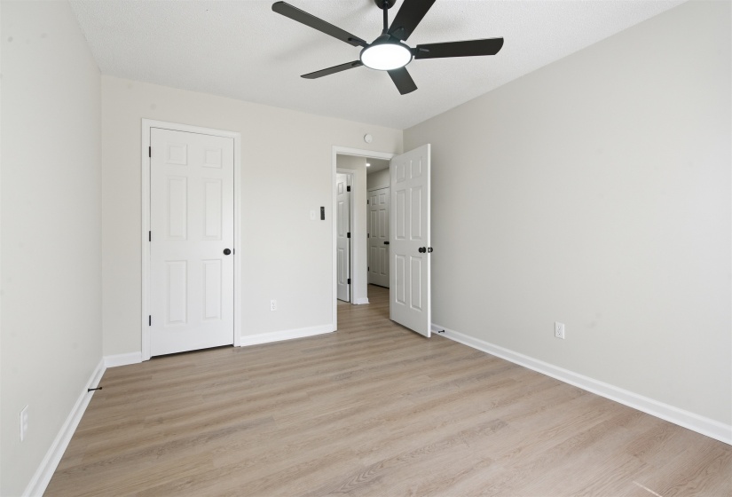 Spacious interior room featuring light wood-finish flooring, crisp white baseboards, and neutral wall tones