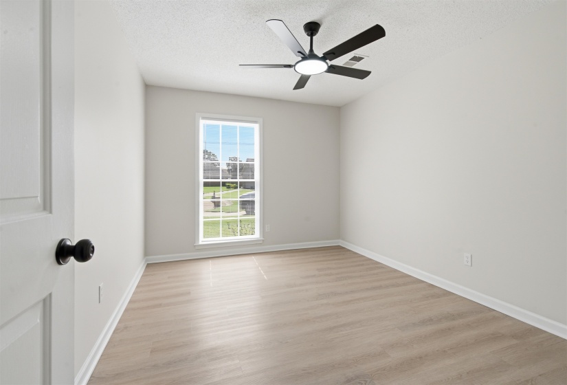 Room featuring light wood-finish flooring, white walls, and a modern ceiling fan