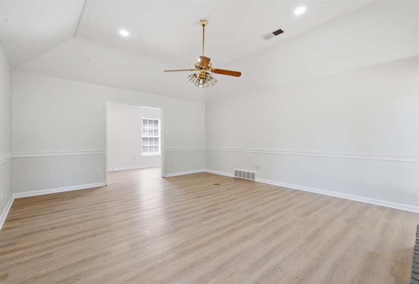 Spacious interior room featuring light wood-finish flooring, vaulted ceilings, and recessed lighting
