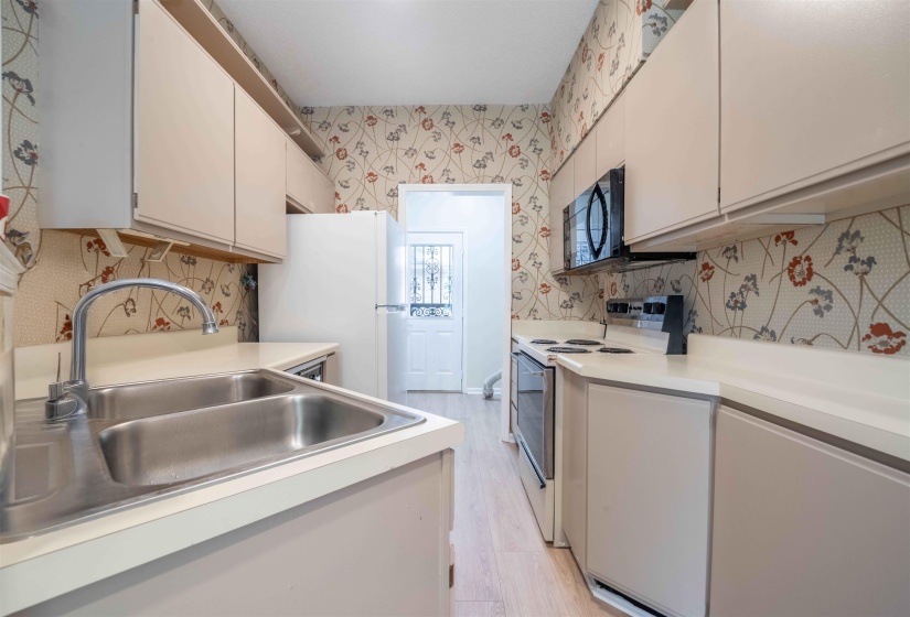 Galley kitchen featuring light-toned cabinetry, light countertops, and a double basin stainless steel sink with a high-arch faucet