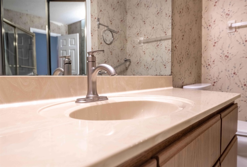 Bathroom vanity featuring an integrated beige sink, a brushed nickel faucet, and wood-finish cabinetry