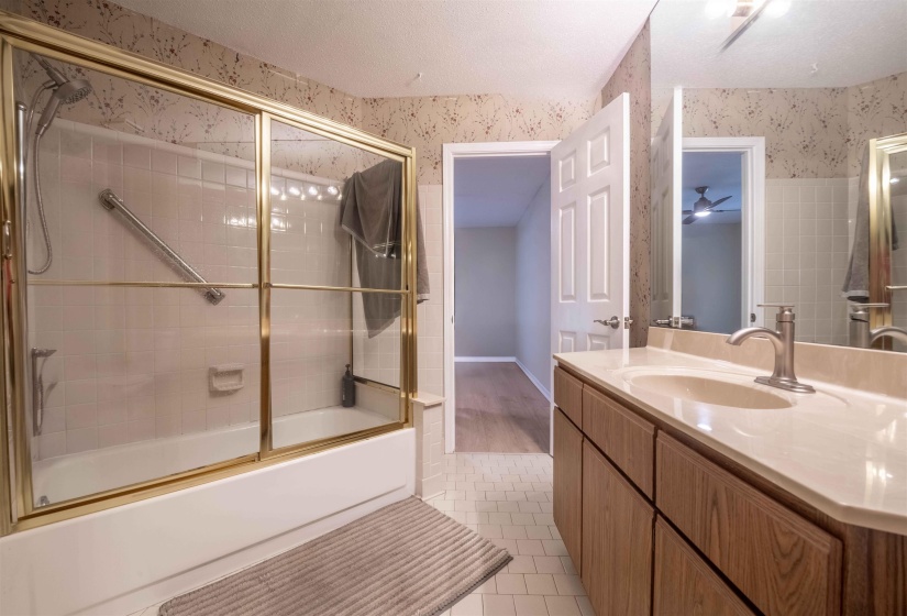 Bathroom featuring a tub and shower combination with gold-tone framed glass doors