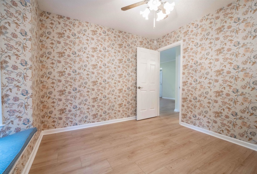 Room featuring floral wallpaper and wood-finish flooring