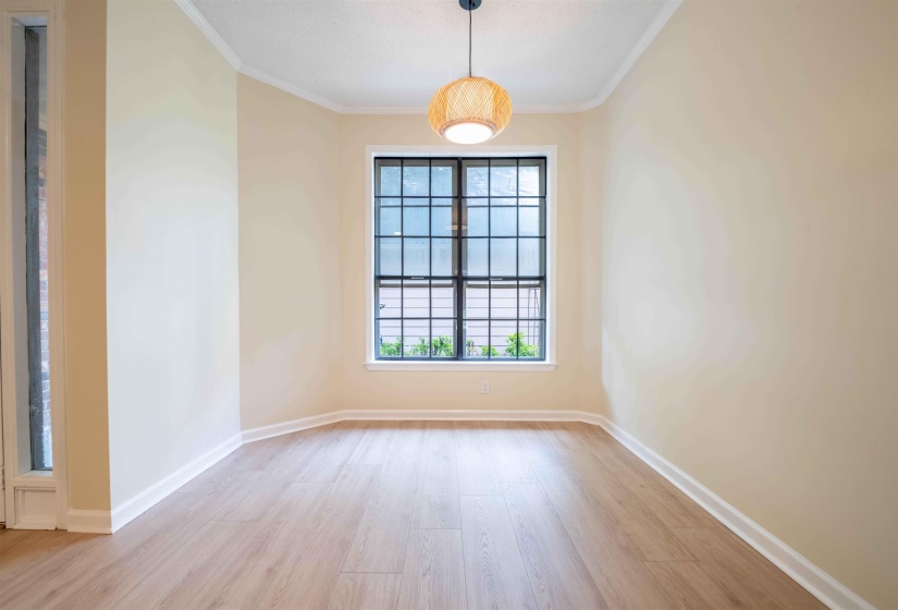 Recessed wall with a large grid-patterned window, wood-finish flooring, and a decorative pendant light fixture
