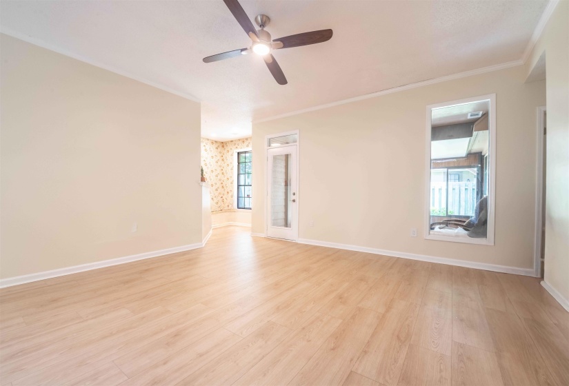 Spacious room featuring wood-finish flooring, light-toned walls, and a ceiling fan