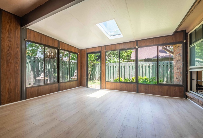 Sunroom featuring wood-finish wall panels and light wood-finish flooring