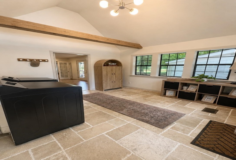 Vaulted ceiling featuring an exposed beam, a modern chandelier, and ample natural light from multiple windows