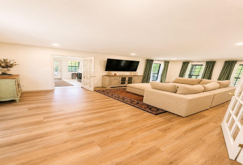 Spacious room featuring light wood-finish flooring, recessed lighting, and white walls