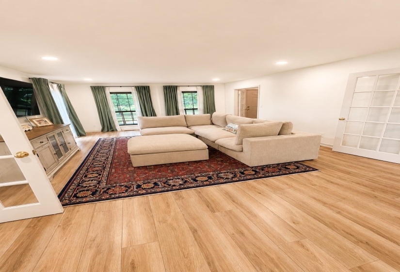 Light wood-finish flooring throughout, featuring recessed lighting, white walls, and French doors