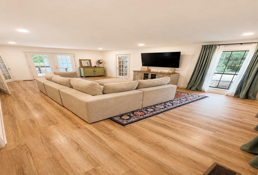 Spacious living area featuring wood-finish flooring, recessed lighting, and multiple French doors