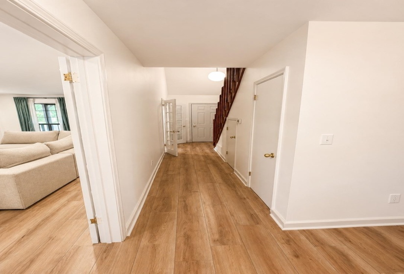 Hallway featuring wood-finish flooring, white painted walls, and white trim