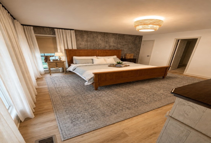 Spacious room featuring wood-finish flooring, a textured accent wall, and a woven flush-mount ceiling light
