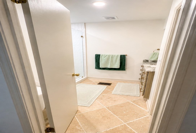 Bathroom featuring diagonal tile flooring, a glass-enclosed shower, and a vanity with a stone countertop