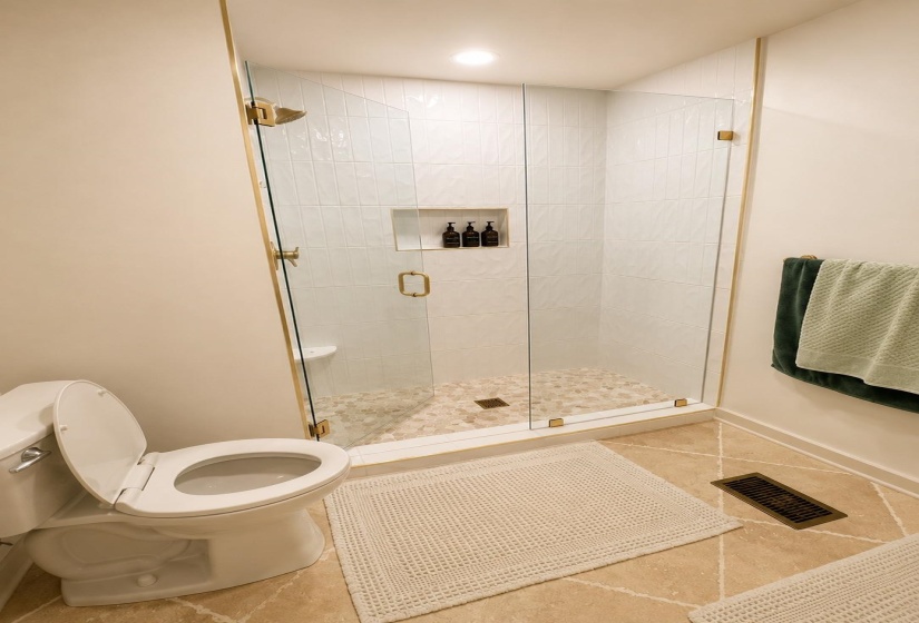 Walk-in shower with clear glass enclosure and gold-finish hardware