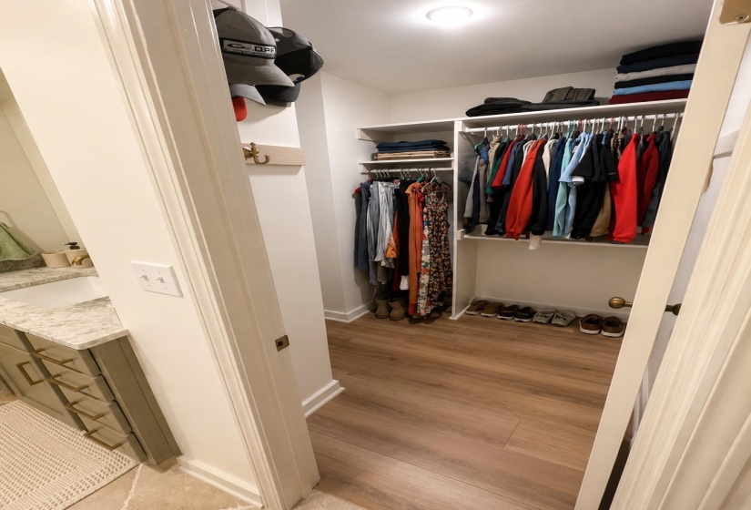 Walk-in closet featuring built-in shelving, hanging rods, and wood-finish flooring