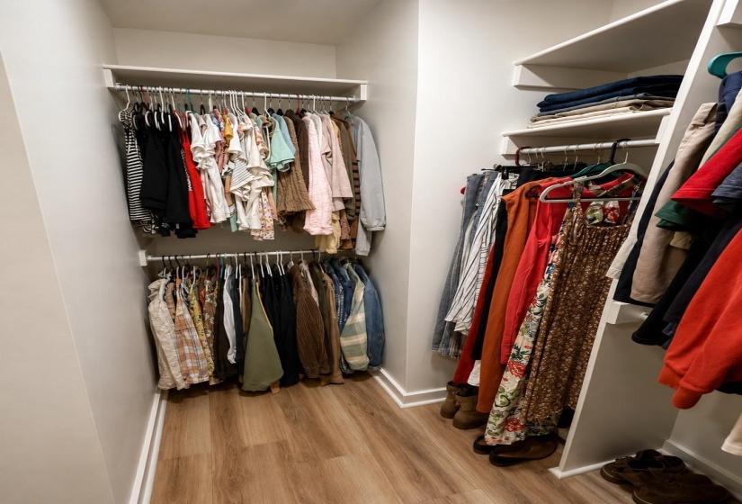 Walk-in closet featuring built-in shelving, dual hanging rods, and wood-finish flooring