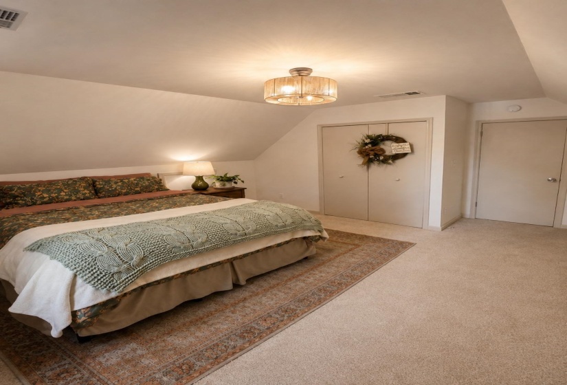 Bedroom featuring sloped ceilings, a semi-flush mount ceiling light fixture, neutral carpeting, and bi-fold closet doors