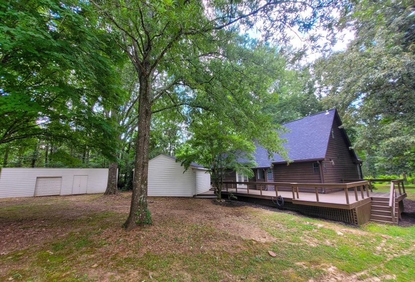 Exterior featuring a brown siding, dark shingle roof, and an expansive wood deck with railing