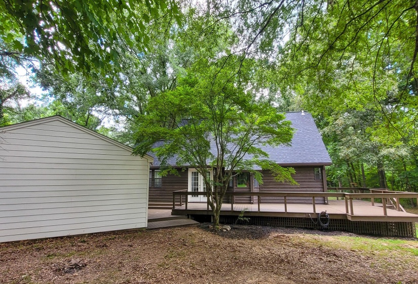 Expansive wood-finish deck with railings, set against a dark-paneled exterior and a new dark shingle roof