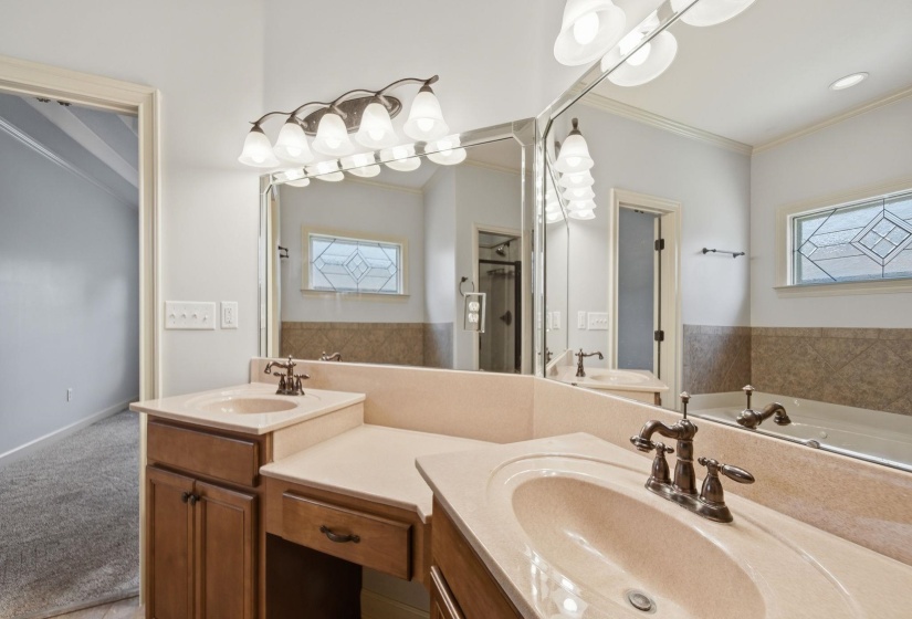 Bathroom featuring a double vanity with integrated sinks, a built-in makeup counter, full-width mirror, and a decorative stained-glass window