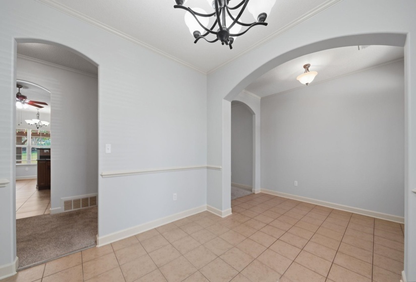 Formal Dining Room featuring tile flooring, neutral wall tones, crown molding, and an arched doorway
