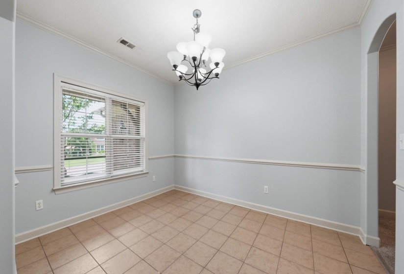 Formal Dining Room featuring tile flooring, a large window with blinds, crown molding, chair rail molding, and a chandelier light fixture