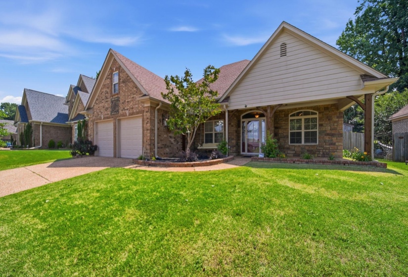 Brick and stone veneer exterior featuring a two-car garage, arched entry, and gabled roofline