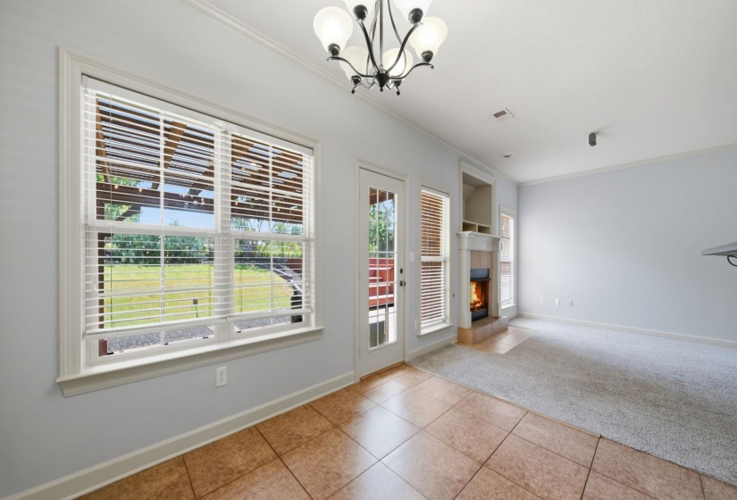 Expansive window with blinds overlooking a landscaped backyard, dual-pane glass door, tile flooring.