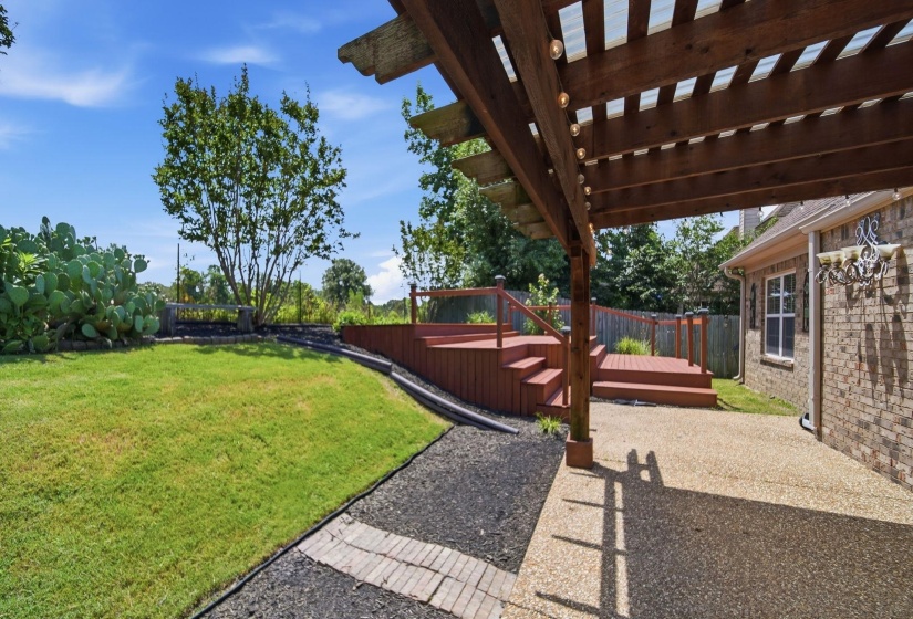 Outdoor living space featuring a wood pergola with integrated lighting, a tiered wood deck with railings, a concrete patio, and a manicured lawn