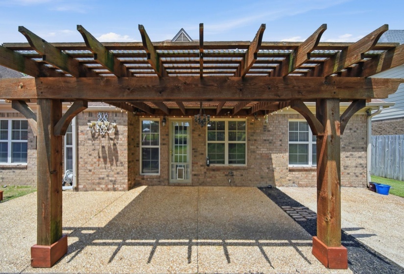 Expansive pergola-covered patio featuring a wood-finish structure and exposed aggregate concrete flooring