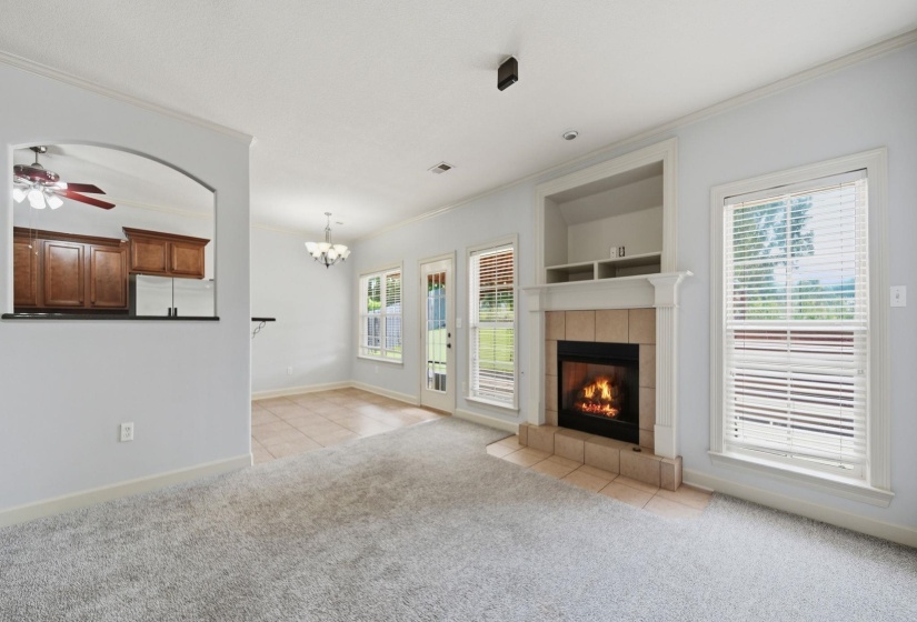 Great Room featuring a fireplace with gas logs ,tile surround and mantel, built-in shelving, windows with blinds, and light-toned carpeting