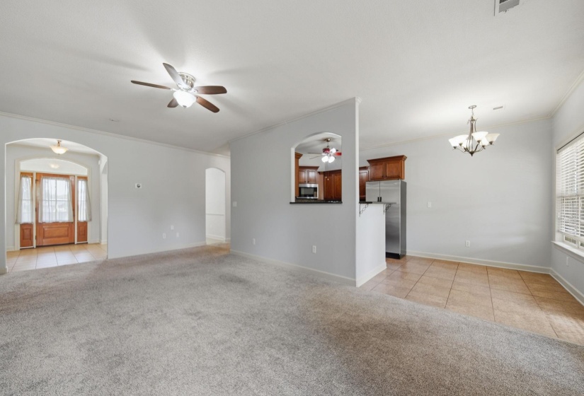 Great Room featuring a ceiling fan, arched doorways, and a pass-through opening to the kitchen