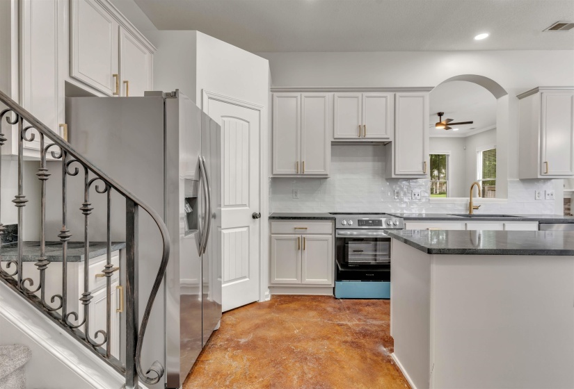 Kitchen featuring white shaker-style cabinetry, dark countertops, a stainless steel electric range, and a gold-finish gooseneck faucet