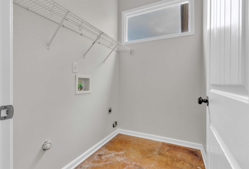 Utility space featuring light gray walls, an upper transom window, white wire shelving, and all necessary hookups