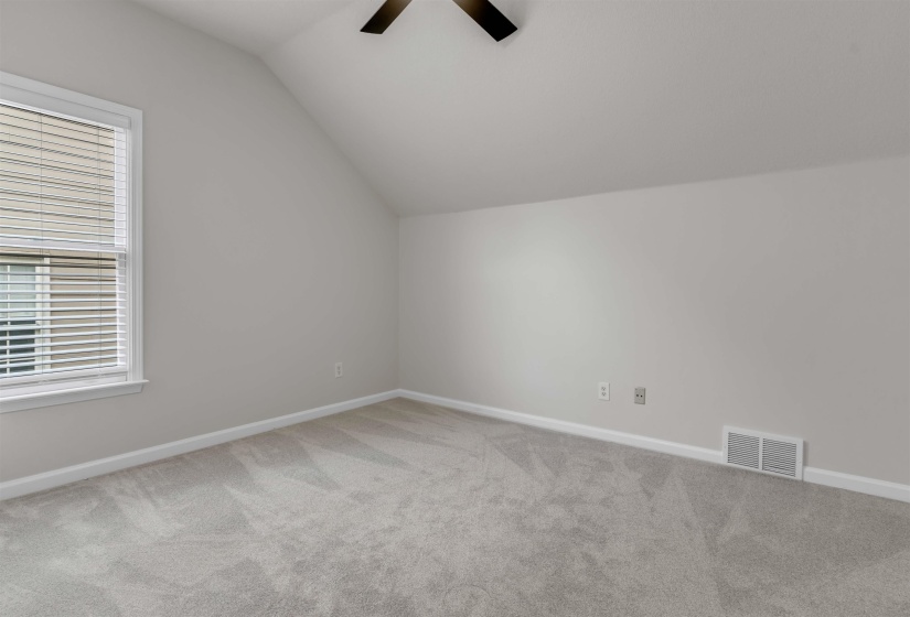 Room featuring a vaulted ceiling, light gray carpeting, and a white-framed window with blinds