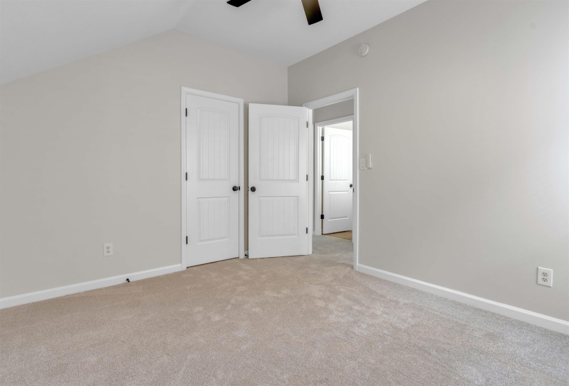 Carpeted room featuring a neutral color palette, white baseboards, and a black ceiling fan