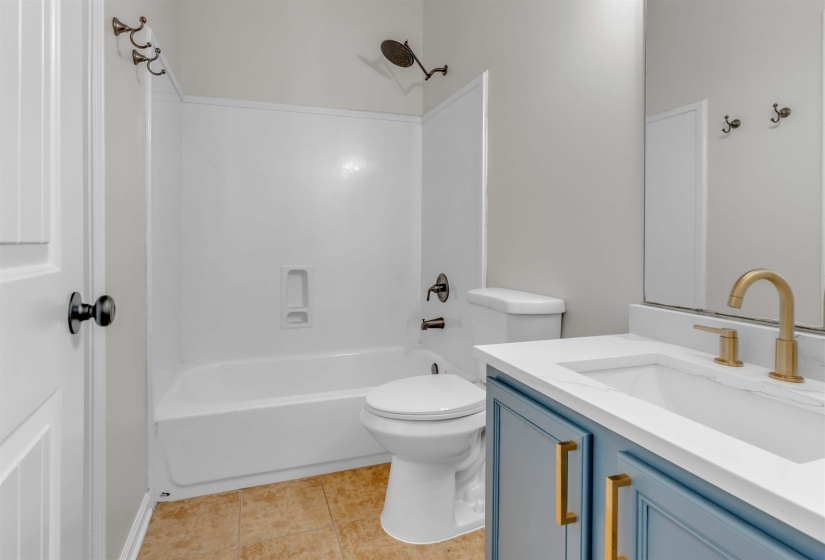 Bathroom vanity featuring a vessel sink, quartz countertop, and gold-finish fixtures