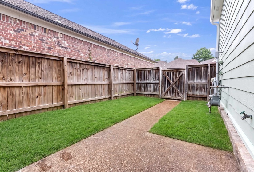Private fenced yard with a concrete pathway and maintained lawn