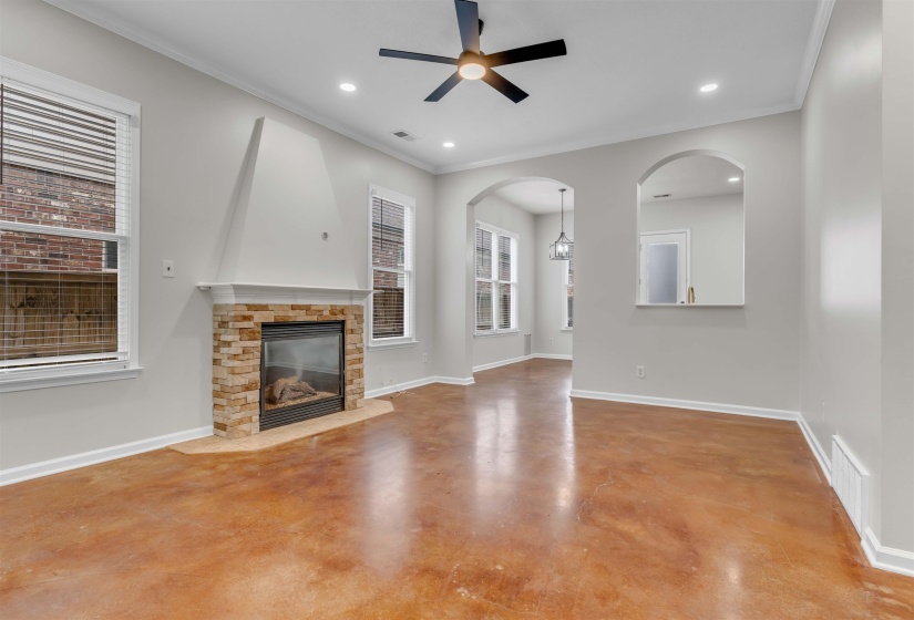 Living space featuring stained concrete flooring, a fireplace with stacked stone surround and a white mantel, recessed lighting, and a ceiling fan