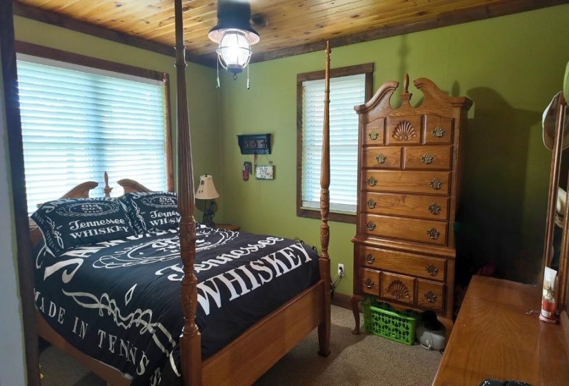 Bedroom featuring wood-finish ceiling, green wall paint, and a window with blinds