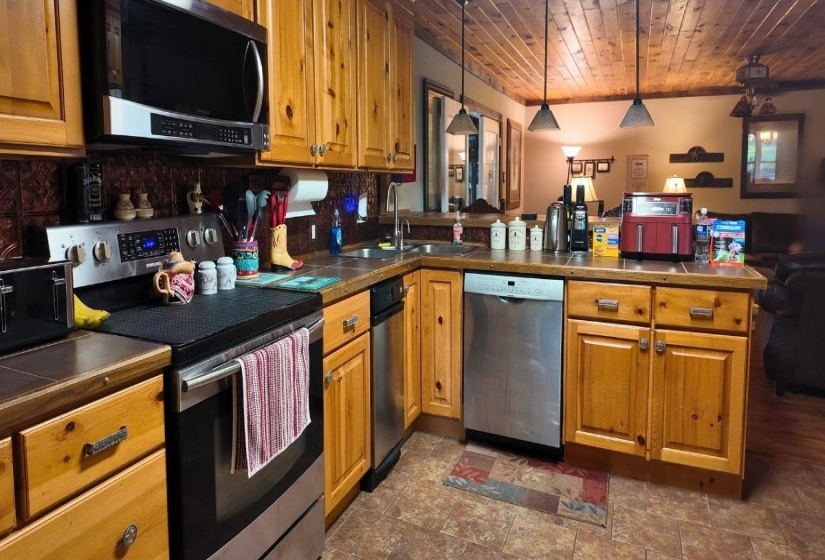 Kitchen featuring wood cabinetry, stainless steel appliances, a tile backsplash, and a wood-paneled ceiling