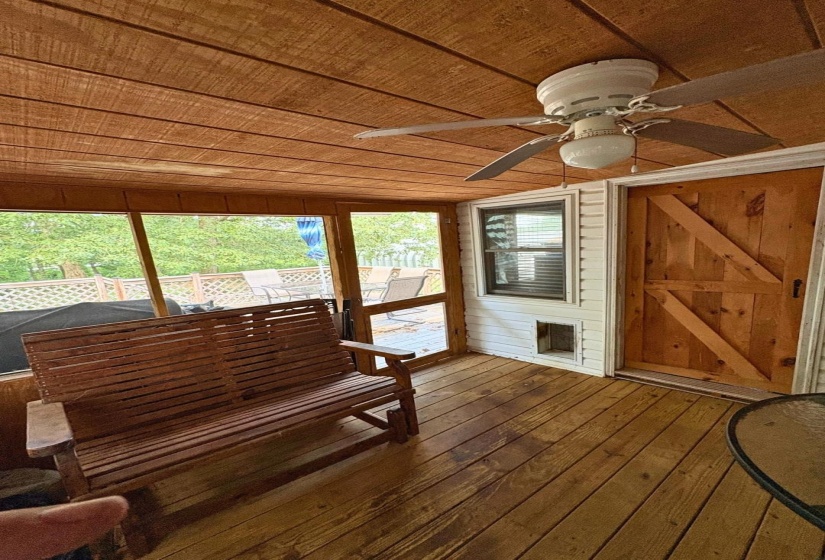 Screened porch featuring a wood-finish plank ceiling and flooring, a ceiling fan with integrated lighting, and a barn-style wood door