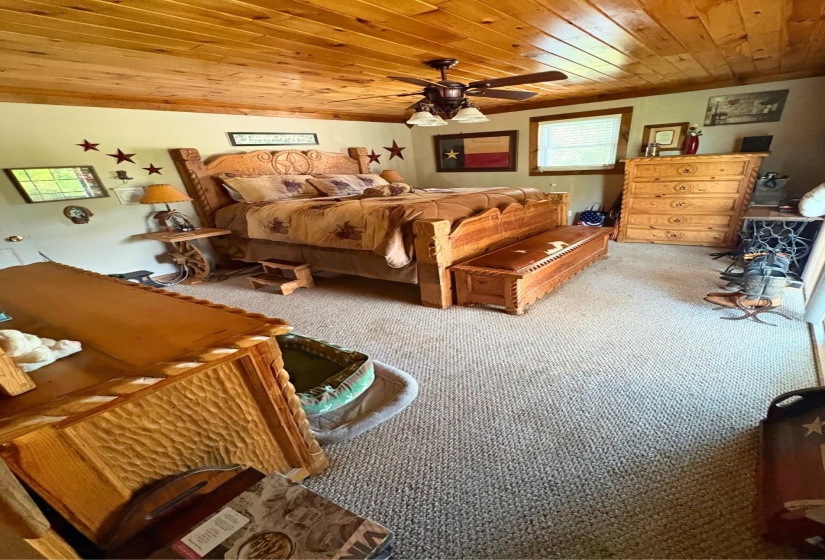 Carpeted room featuring a wood-planked ceiling, ceiling fan with light fixture, and neutral wall tones