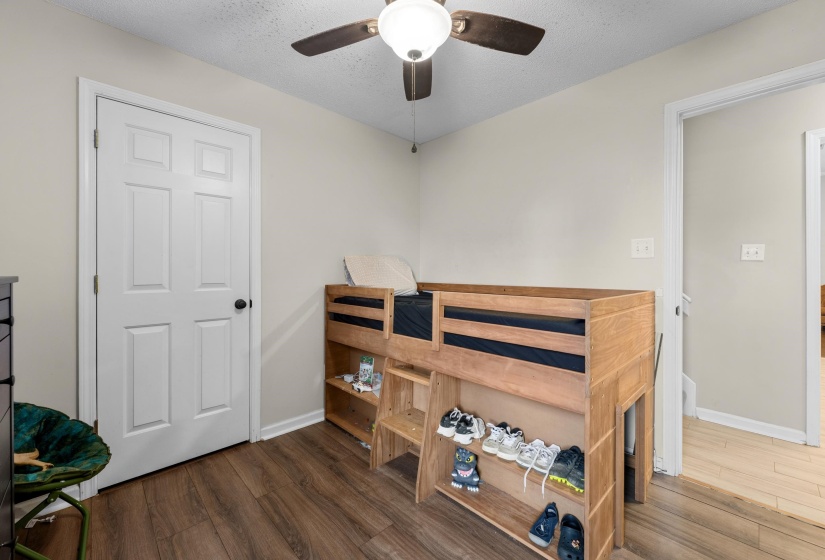 Room featuring light neutral wall paint, wood-finish flooring, a white paneled door, and a ceiling fan with integrated lighting