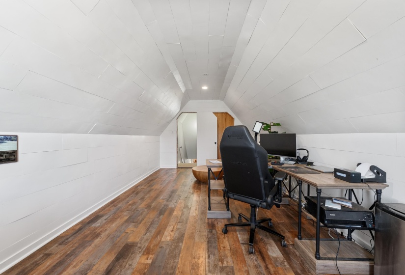 Expansive attic space featuring pitched white shiplap walls and ceiling, recessed lighting, and wood-finish flooring