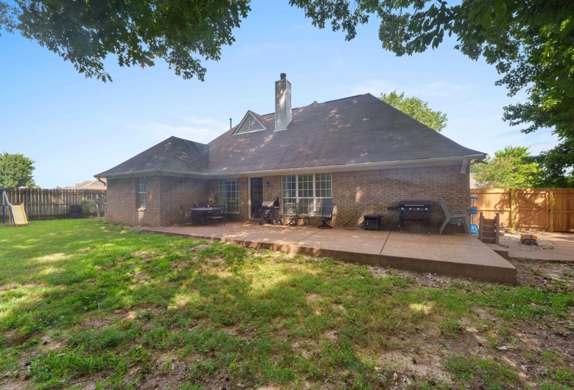 Brick exterior featuring a multi-level concrete patio, a chimney, and a dormer window