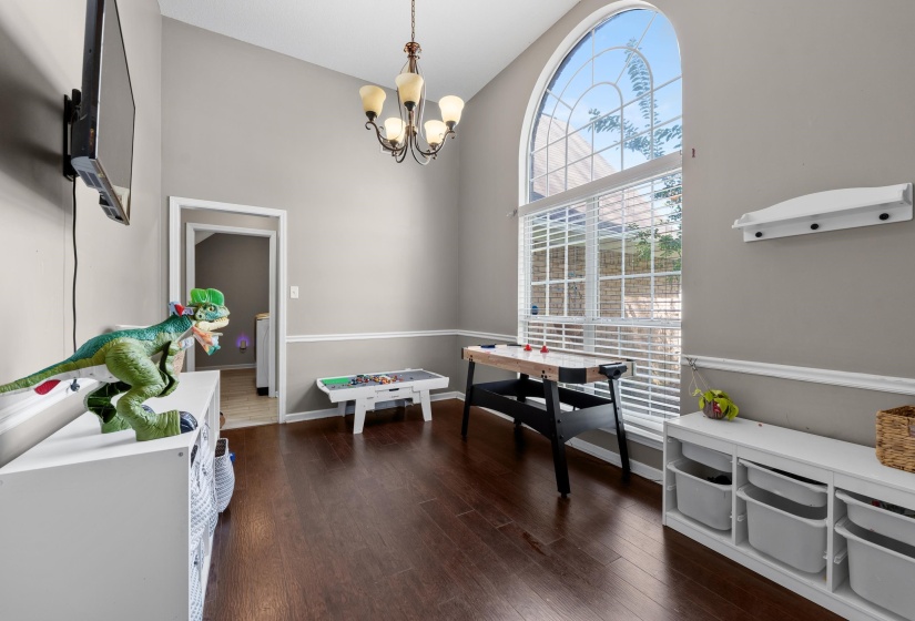 Two-story room featuring a grand arched window, wood-finish flooring, neutral wall tones, and a chandelier