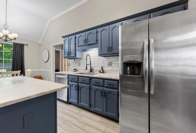 Kitchen featuring blue cabinetry, light countertops, subway tile backsplash, and light wood-finish flooring